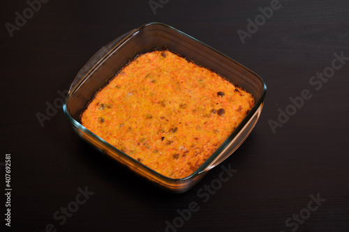 Carrot casserole with raisins in a glass pan on a dark wooden surface
