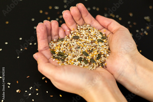 Cereal mix held in a woman hand. Black background.