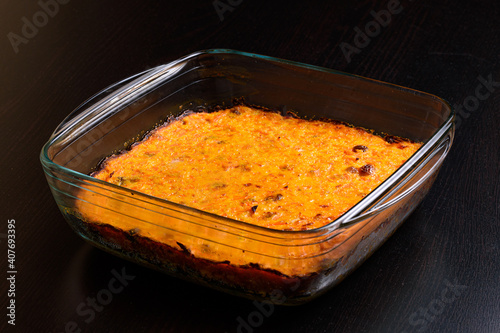Carrot casserole with raisins in a glass pan on a dark wooden surface