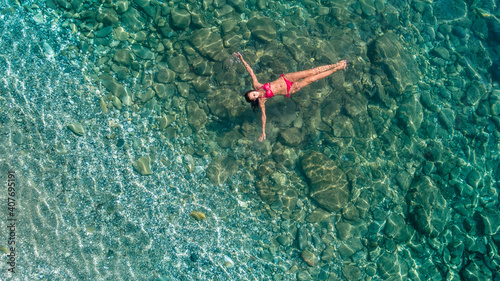Aerial view of swimming woman in clear azure water, blue lagoon.  Spain, Roses.