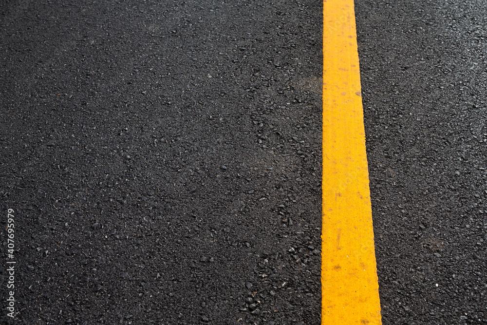 Fototapeta premium Close up black asphalt road surface texture with a yellow line.