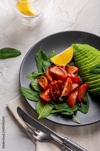 Vegetable salad with tomatoes, avocado and spinach in a grey plate. Healthy lifestyle concept