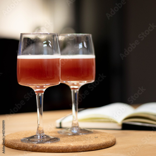 Wine glass with cocktail on wood table and book in background