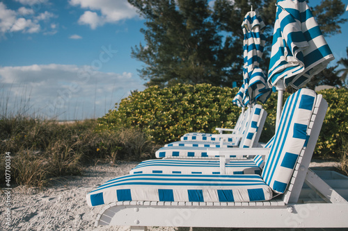 Row of Blue and White Striped Deck Chairs on Sandy Beach