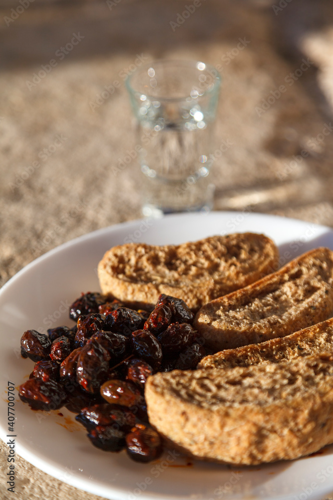 Ταπετσαρία Cretan rusks, olives and tsikoudia (raki), a delicious snack meal as often offered in Crete