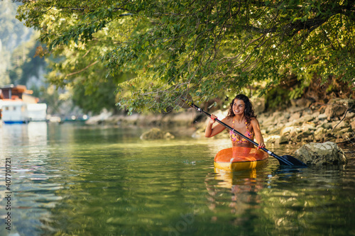 Female in bikini kayaking on lake during sunny day