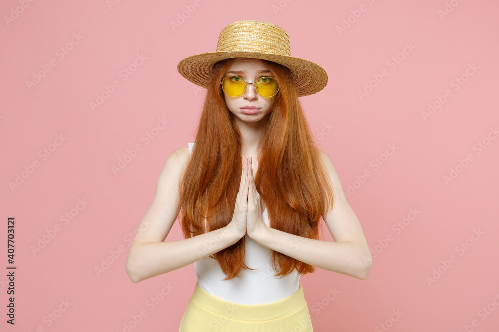 Young pleading hopeful nice woman 20s ginger long hair in straw hat glasses summer clothes hands folded in prayer gesture, begging about something isolated on pastel pink background studio portrait. Young pleading hopeful nice woman 20s ginger long hair in straw hat glasses summer clothes hands folded in prayer gesture, begging about something isolated on pastel pink background studio portrait.