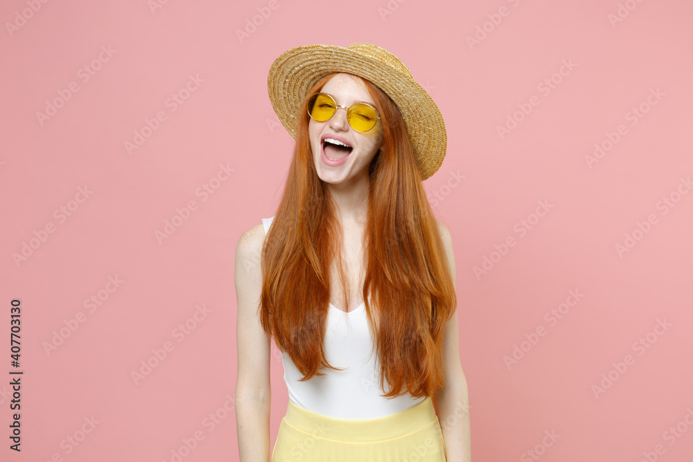 Young smiling happy caucasian redhead attractive woman 20s ginger long hair wearing straw hat glasses summer clothes blinking looking camera isolated on pastel pink color background studio portrait Young smiling happy caucasian redhead attractive woman 20s ginger long hair wearing straw hat glasses summer clothes blinking looking camera isolated on pastel pink color background studio portrait