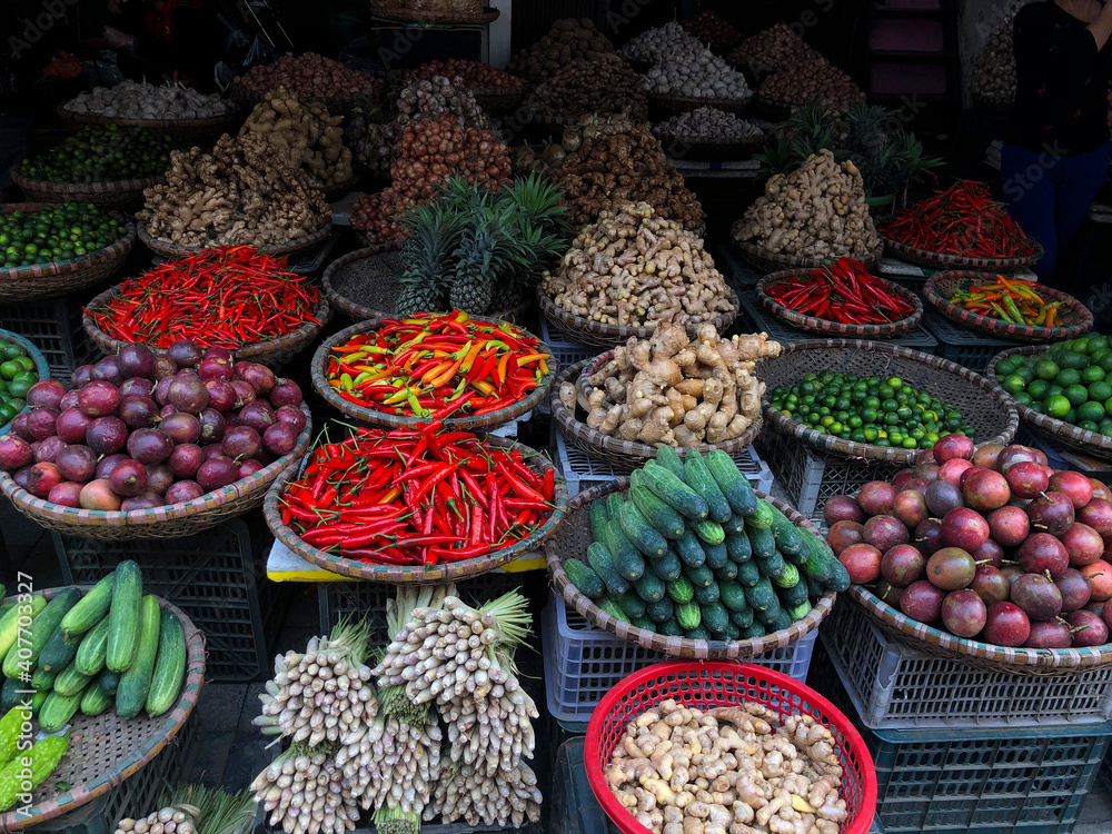 Hanoi, Vietnam, January 30, 2020 - View on a seller in the middle of a large assortment of row loose vegetables and fruits for sale in a street. Short circuit production