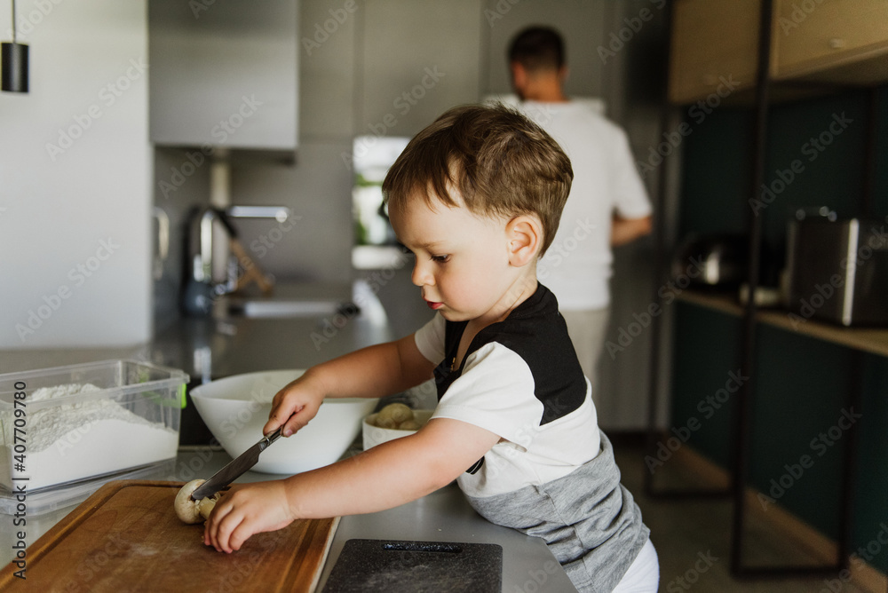 A little boy cuts mushrooms in the kitchen. A little boy cuts mushrooms in the kitchen.