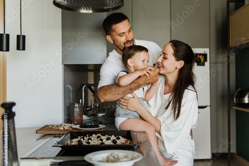 Young parents with their little son cook in the kitchen.