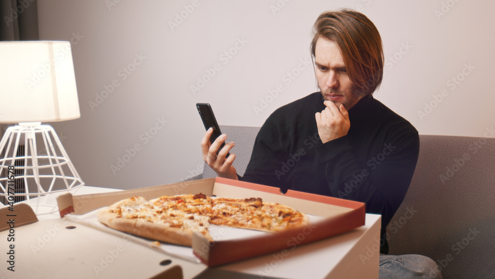 Young caucasian man having a complaint about pizza. Holding smartphone to call customer support. High quality photo Young caucasian man having a complaint about pizza. Holding smartphone to call customer support. High quality photo