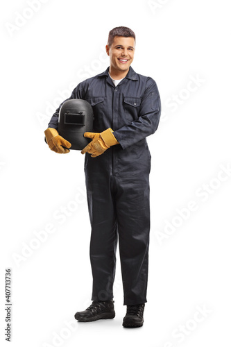 Fototapeta Full length portrait of a welder in a uniform holding a protective helmet and sm