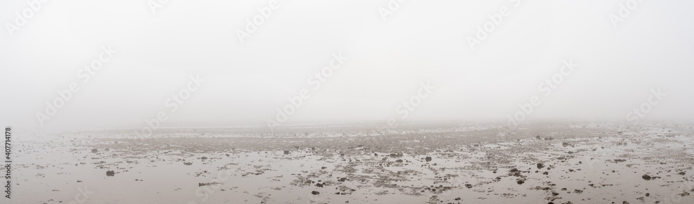 panorama landscape of thick fog over endless wadden sea beach at low tide