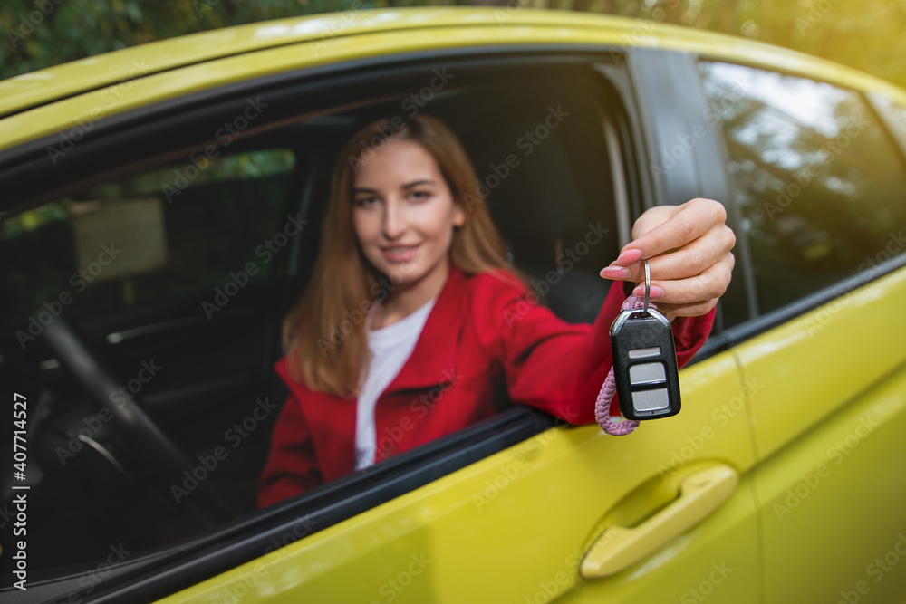 Young woman holds out the car keys through the driver's seat window. Focus on keys