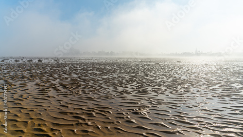 panorama landscape of fog lifting over an endless wadden sea beach at low tide