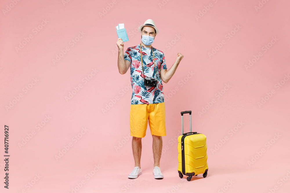 Full length happy traveler tourist man in mask safe from coronavirus hold passport tickets doing winner gesture isolated on pink background. Passenger travel on weekend. Air flight journey concept. Full length happy traveler tourist man in mask safe from coronavirus hold passport tickets doing winner gesture isolated on pink background. Passenger travel on weekend. Air flight journey concept.