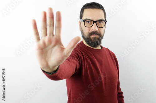 Bearded man with serious face wearing casual clothes and glasses doing stop sign with palm of the hand. Warning expression with negative gesture 