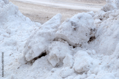 Large pieces of snow cleared from the snowy road to the side of the road.