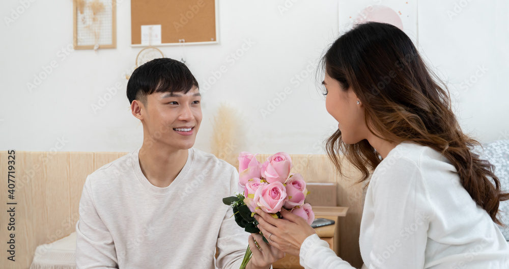 Asian young man surprises his woman on Valentine's Day. He is kneeling and giving a bouquet of pink flowers to his girlfriend Asian young man surprises his woman on Valentine's Day. He is kneeling and giving a bouquet of pink flowers to his girlfriend