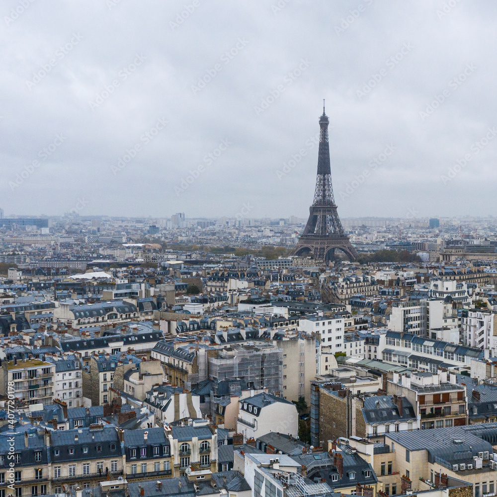 Fototapeta premium View on Eiffel tower over the roofs of Paris on a grey cloudy da