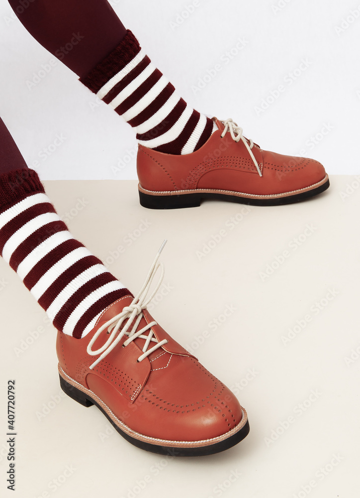 Unrecognizable woman legs wearing retro brown shoes and stripped socks. Fashion vintage shop concept Unrecognizable woman legs wearing retro brown shoes and stripped socks. Fashion vintage shop concept