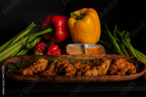 fried fish for a restaurant menu or advertisement yellow pepper and red pepper and scotch bonnet pepper on the side