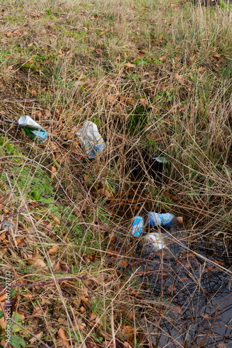Environmental pollution: cans and plastic bottles carelessly thrown in a ditch