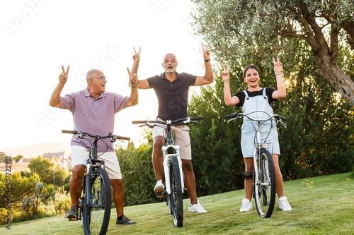 Tre persone di generazioni diverse si divertono ad andare in bicicletta in un prato verde