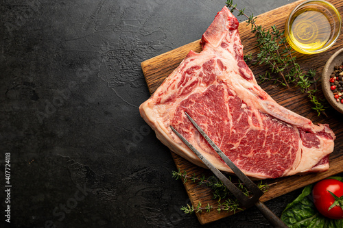 Raw fresh meat T-bone beef Steak and butcher knife on black background, top view