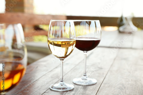 Glasses with different wines on wooden table in outdoor cafe