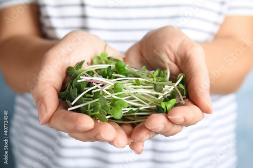 Woman holding fresh organic microgreen, closeup view