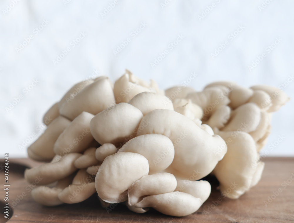 Bunch of brown fresh raw oyster mushrooms on wooden cut board. concept of veggie and raw food. selective focus. vegetable diet. protein and fiber source. Bunch of brown fresh raw oyster mushrooms on wooden cut board. concept of veggie and raw food. selective focus. vegetable diet. protein and fiber source.