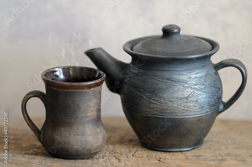 A table on which there is a mug of tea and a kettle.