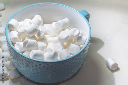 White sweet marshmallow marshmallows in a blue plate on the table.