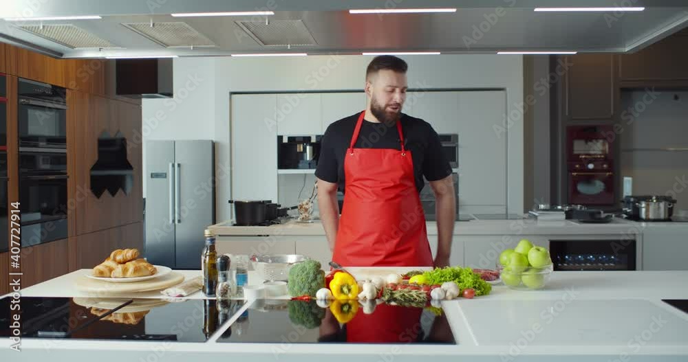 Food blogger looking at camera and talking recording video for blog and cooking online in kitchen