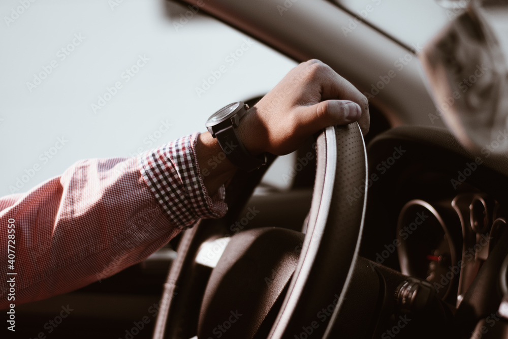 A man holds the steering wheel of his car