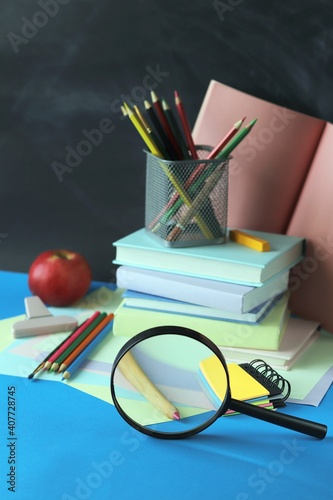 Back to school, stack of books, magnifying glass and stationery on table 