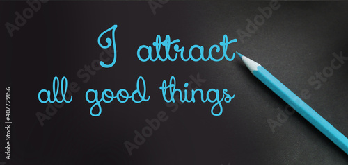 I attract all good things - positive affirmation words - handwriting on a black paper with blue pencil. Law of attraction concept photo