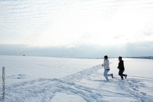 Couple is jogging in the snowy field during a cold winter afternoon as part of the daily routine