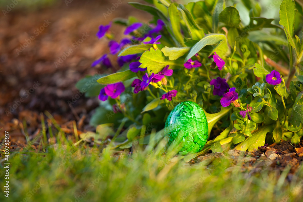 an green easter egg in the garden with purple flowers an green easter egg in the garden with purple flowers