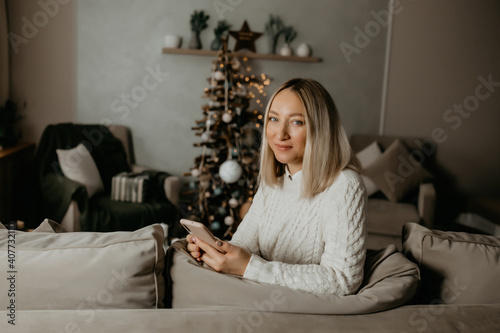 smiling girl with a phone in her hands sitting on the couch