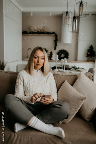 a young girl in white socks, with a phone in her hands, sits on the couch