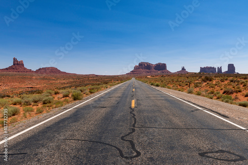 Scenic view of ta road leading to the Monument Valley with sandstone buttes on the background; Concept for travel in the USA and road trip.