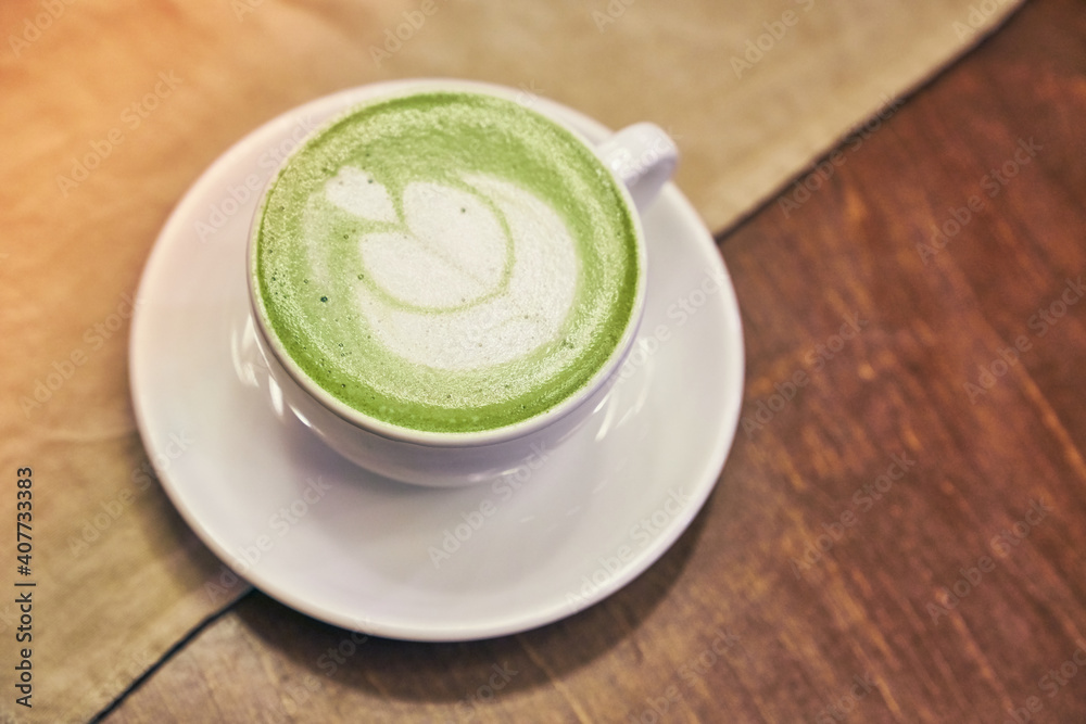 Cup of matcha latte on wooden background and a beige napkin in a cafe with copy space. High quality photo Cup of matcha latte on wooden background and a beige napkin in a cafe with copy space. High quality photo