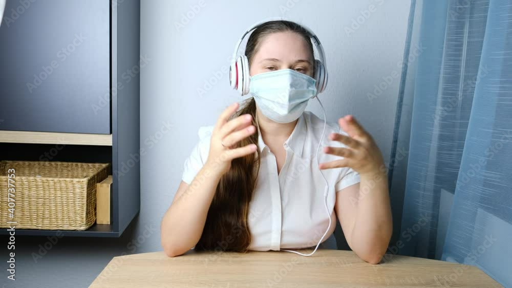 girl with long hair wearing headphones, medical mask leading a conference, discussion on video from home office, concept of remote education, video conference, foreign language lesson girl with long hair wearing headphones, medical mask leading a conference, discussion on video from home office, concept of remote education, video conference, foreign language lesson