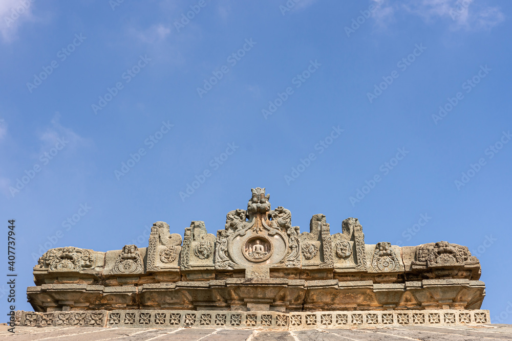 Lakkundi, Karnataka, India - November 6, 2013: Brahma Jinalaya temple. Closeup of sculpted gable above roof under blue sky.