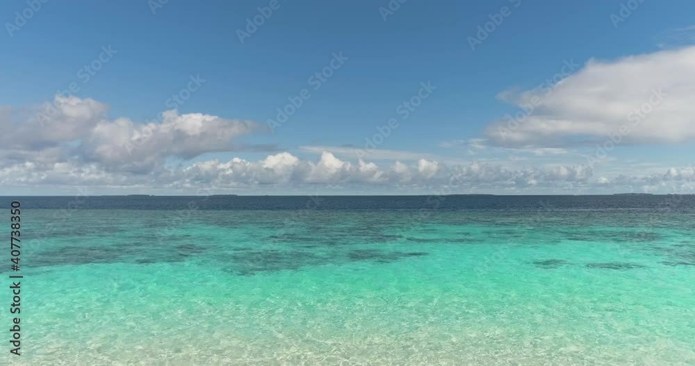 The drone slowly flies out from behind the bushes to the beach on the coastline to the sea horizon in the Maldives in sunny weather. The drone slowly flies out from behind the bushes to the beach on the coastline to the sea horizon in the Maldives in sunny weather.