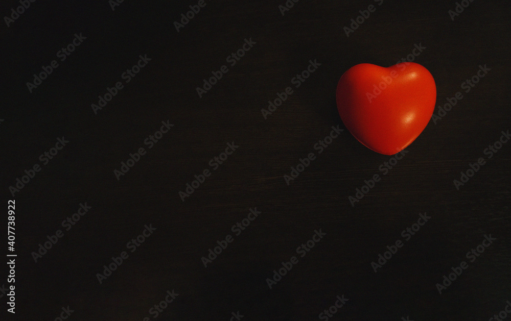 Red heart on a black abstract background with a light wood texture. Copy space. Red heart on a black abstract background with a light wood texture. Copy space.