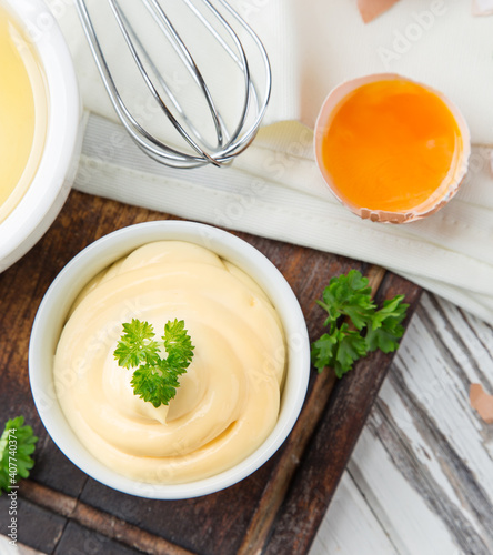 Bowl of Mayonnaise sauce on white wooden table, close-up